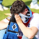 Ein enttäuschter HSV-Fan vergräbt sein Gesicht in seinem Schal.