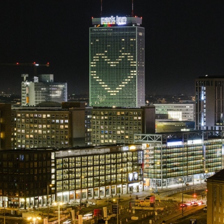 Eine Panoamansicht zeigt Berlin-Mitte am Abend. Im höchsten Gebäude, dem Hotel Park Inn, leuchtet in der Corona-Krise ein Herz geformt aus Lichtern der derzeit nicht buchbaren Hotelzimmer.