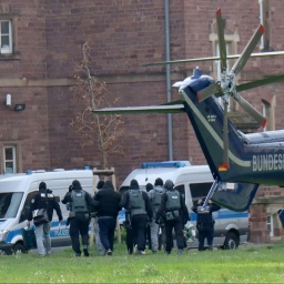 Vermummte Polizist*innen führen ein Gruppe Leute ab.