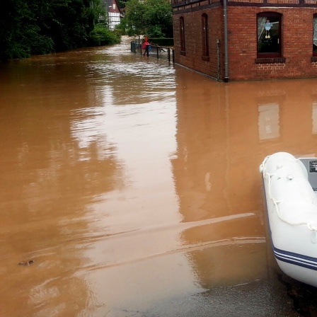 Ein Schlauchboot liegt neben einer überfluteten Straße in Bornhausen bei Seesen.