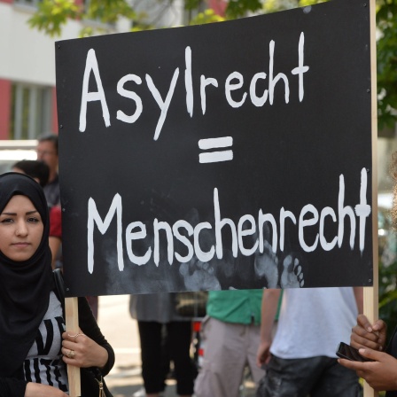 Teilnehmer einer Demonstration protestieren mit einem Schild mit der Aufschrift «Asylrecht = Menschenrecht