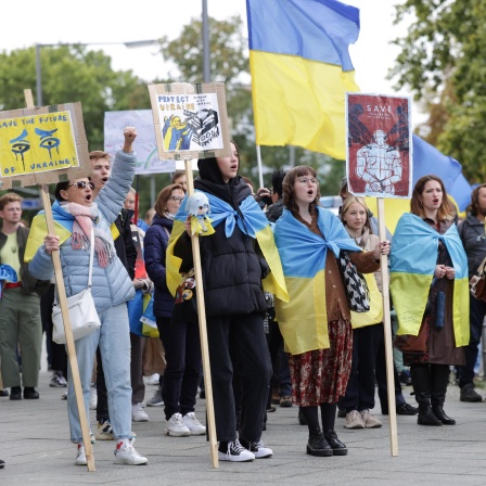Teilnehmerinnen demonstrieren gehüllt in ukrainische Nationalfahnen vor dem Bundesverteidigungsministerium für Panzerlieferungen an die Ukraine. Organisiert ist die Demonstration von der Organisation "Vitsche".