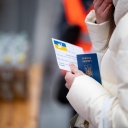 Eine junge Frau aus der Ukraine steht mit ihrem Pass in der Hand ein einer Schlange.