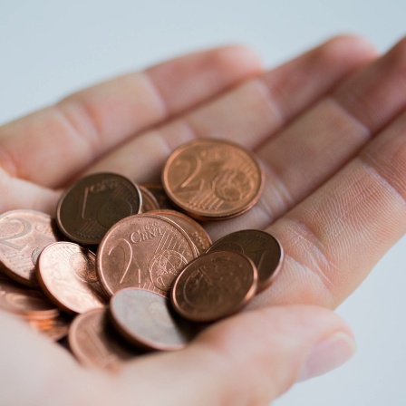 In einer Hand liegt ein Haufen von 1- und 2-Cent-Münzen