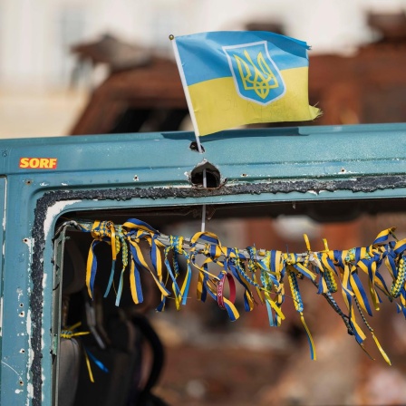 Eine kleine ukrainische Flagge March am einem zerstörten russischen Fahrzeug, das in Kiew im Stadtzentrum ausgestellt steht. 