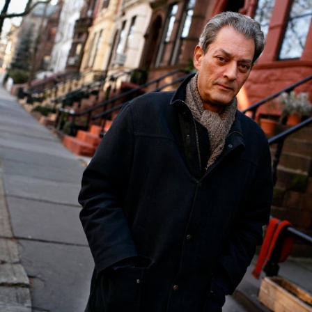 Paul Auster vor seinem Haus in Brooklyn. Er trägt eine schwarze Jacke und Schal.