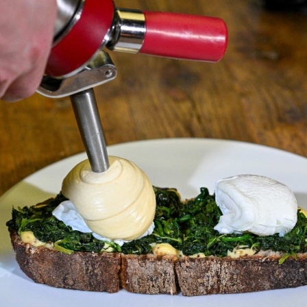 Eggs Benedict aus pochierten Eiern, Miso-Hollandaise, Spinat und Wildkräutern werden auf Sauerteigbrot im Bonvivant Cocktail Bistro in Berlin-Schöneberg angerichtet. 