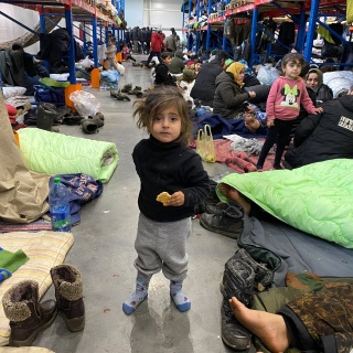 Migranten sind in der Notunterkunft in der Lagerhalle eines Logistikzentrums nahe der Grenze zu Polen untergebracht. Bild: Kleines Mädchen umgeben von Behelfs-Betten