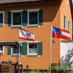 Eine Reichsfalle und die Stars-and-Bars-Flagge der US-Südstaaten wehen vor einem Wohnhaus.