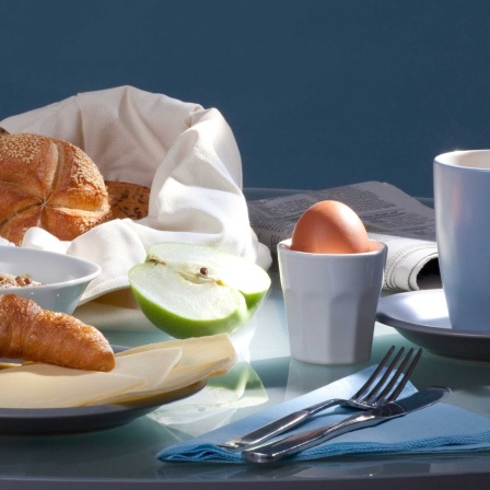 Frühstückstisch mit Kaffe, Ei, Croissant, Brötchen, Käse