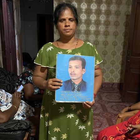 Eine Frau in Sri Lanka hält das Bild ihres vermissten Ehemanns hoch.