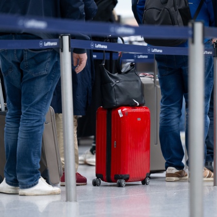 Passagiere mit Koffern am Flughafen.