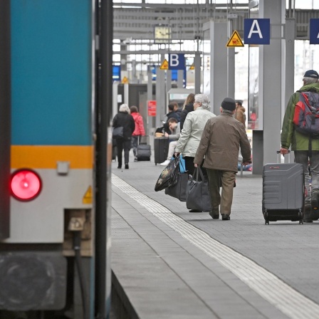Bahnreisende gehen mit ihrem Gepäck auf einem Bahnsteig am Hauptbahnhof in München