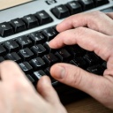 Ein Mann tippt auf der Tastatur eines Computers