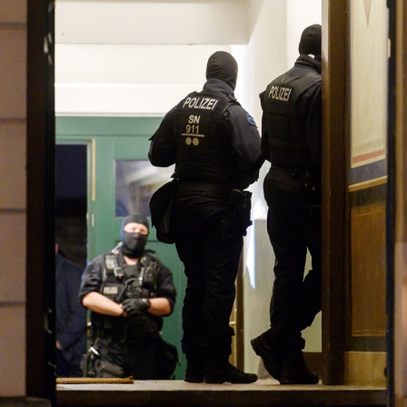 Polizisten stehen bei einer Razzia in einem Haus im Stadtteil Pieschen. Nach Drohungen gegen Sachsens Ministerpräsidenten Kretschmer auf Telegram durchsucht die Polizei in Dresden mehrere Objekte.