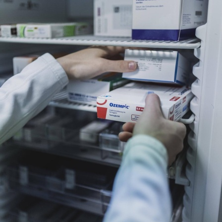Ein Mensch mit weißem Kittel nimmt in einer Apotheke in Niesky eine Packung Ozempic, ein Antidiabetikum zur Gewichtskontrolle, aus einem Schrank.