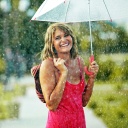 Eine junge Frau mit Schirm in einem Sommerregen