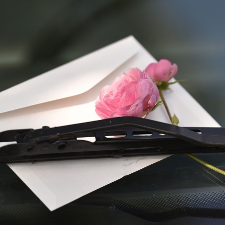 Ein Liebesbrief mit Rose an die Windschutzscheibe geklemmt