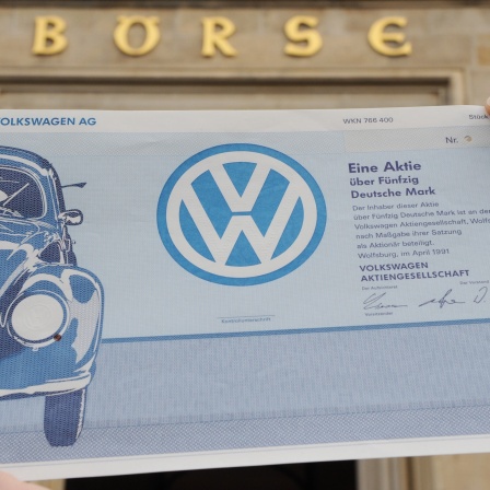 Ein Mitarbeiter der Niedersächsischen Börsen AG hält vor dem Börsengebäude in Hannover ein historisches Wertpapier der Volkswagen AG in der Hand (Archivbild)