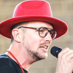 Ees, ein deutschnamibischer Musiker und Musikproduzent und Superstar aus Namibia, mit rotem Hut am Mikrofon. Nahaufname des Gesichts.