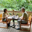 Eine Frau und ein Mann sitzen an einem Tisch vor Mikrofonen. 