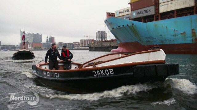 Zwei Männer fahren in einem Festmacherboot durch den Hafen.