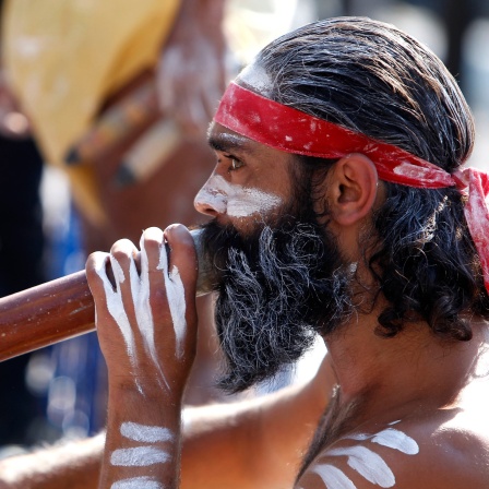 Aborigine bläst in ein Didgeridoo: Seit 1925 kennt man das Blasinstrument der australischen Aborigines in England als Didgeridoo. Die Ursprünge des Instruments liegen allerdings viel länger zurück: 2000 Jahre sagen die Forscher - 40.000 Jahre sagen die Aborigines