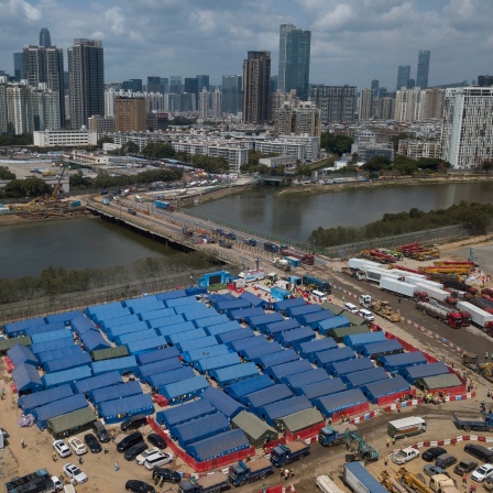 Gebäude mit blauen Dächer sind auf der Baustelle der Corona-Isoliereinrichtung neben der Brücke zwischen der chinesischen Stadt Shenzhen und Hongkong zu sehen. 