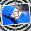 Eine Bildmontage zeigt eine Dartscheibe. Darauf ist eine Postkarte zu sehen. Sie zeigt den Arm eines Fußballers. Er trägt am Arm eine Binde, auf der ein "Verboten"-Zeichen zu sehen ist.