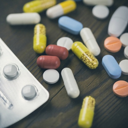 Eine Mischung verschiedener Tabletten und Kapseln liegen neben einem Blister