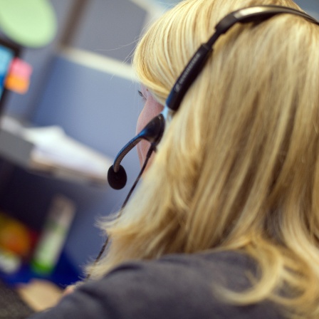 Mit Headset sitzt 2011 eine Mitarbeiterin vor einem Computermonitor in einem Callcenter.