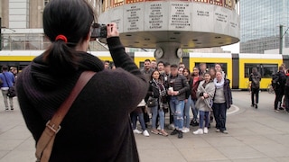 Eine Frau fotografiert eine Gruppe von Jugendlichen auf dem Alexanderplatz in Berlin.
