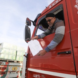 Lkw-Fahrer Mohamed Basyouny zeigt einen Zettel, der auf Juli 2024 datiert ist, als er seinen Lkw zum ersten Mal belud und seitdem nicht mehr passieren konnte, während er in der Lkw-Schlange wartet, um vom Grenzübergang Rafah in die palästinensischen Gebiete zu gelangen. 