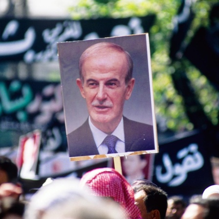 Plakat von Hafiz Al-Assad wird über dem Trauerzug hochgehalten. Tausende Syrer, freiwillig oder delegiert, nehmen am 13.06.2000 an einem Trauermarsch für den am 10. Juni verstorbenen Präsidenten Hafiz Al-Assad teil. Foto: Matthias Tödt