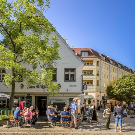 Blick auf den Vorplatz des Wirtshauses. An Tischen sitzen Gäste. Rechts im Bild die typischen Fassaden des Nikolaiviertels