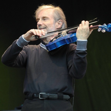 Der Geiger Jean-Luc Ponty spielt lächelnd auf einer blauen Violine.