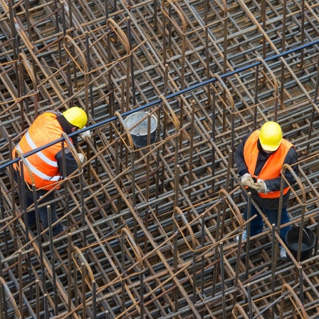 Bauarbeiter errichten auf einer Baustelle ein Stahlgeflecht