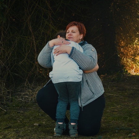 Szene aus dem Film "Im Prinzip Familie": Eine Frau umarmt ein Kind, im Hintergrund spielen andere Kinder.