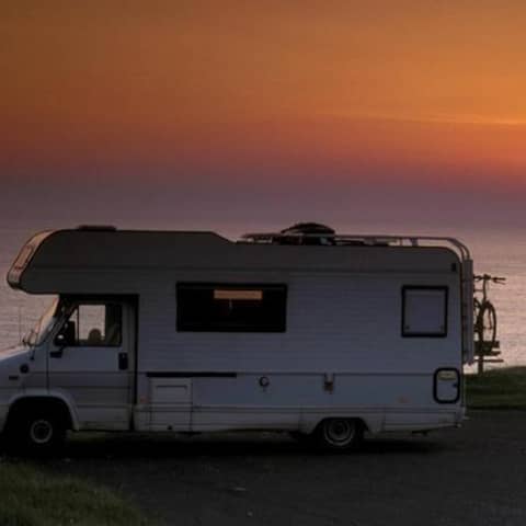 Ein Wohnmobil parkt an einem Strand bei Sonnenuntergang