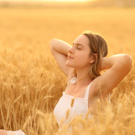 Frau, die sich in einem goldenen Weizenfeld entspannt