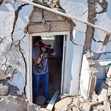 Ein Kameramann filmt in einem zerstörten Gebäude in der Ukraine.