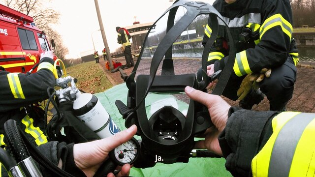Ein Feuerwehrmann zieht sich seine Maske auf, er bereitet sich auf einen Einsatz vor.