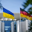 Die Fahne der Ukraine weht zwischen der europäischen (l.) und deutschen Fahne (r.) vor dem Bundeskanzleramt in Berlin.