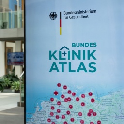 Eine Tafel vor einem Gebäude zeigt ein Werbeplakat für den Bundes-Klinik-Atlas mit einer Deutschlandkarte. 
