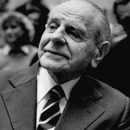 Karl Popper sitzt im Publikum einer Veranstaltung und hört aufmerksam zu