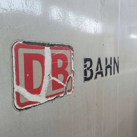 Ein verwittertes Logo der Deutschen Bahn an einem Schnellzug, der in einem Bahnhof steht.