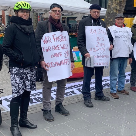 Menschen protestieren mit Plakaten in einer Fußgängerzone.