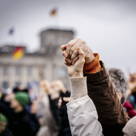 Menschen halten sich am Samstag auf der Großdemo gegen Rechtsextremismus vor dem Reichstag in Berlin an den Händen. 