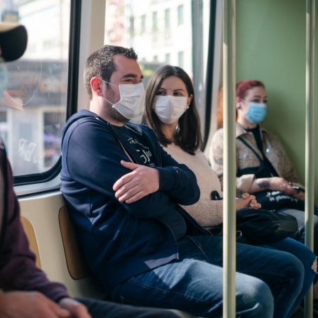 Einige Menschen sitzen mit Mundschutz in der Straßenbahn in Hannover.