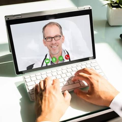 Mann nutzt einen Laptop für eine Videokonferenz mit einem Arzt